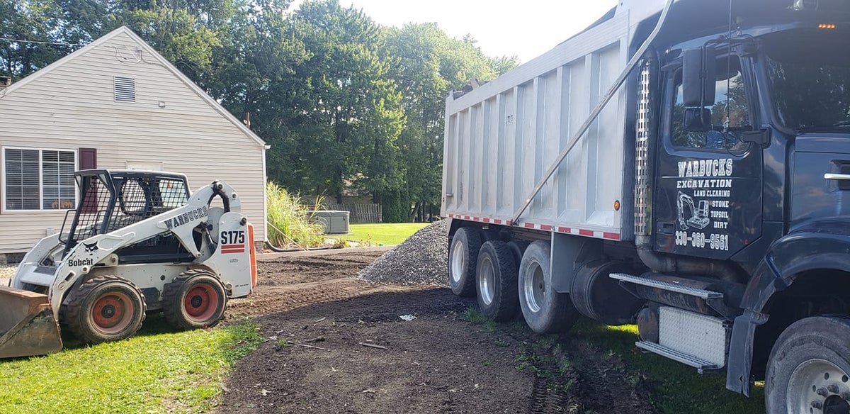 Warbucks skid steer and dump truck placing gravel for a driveway project